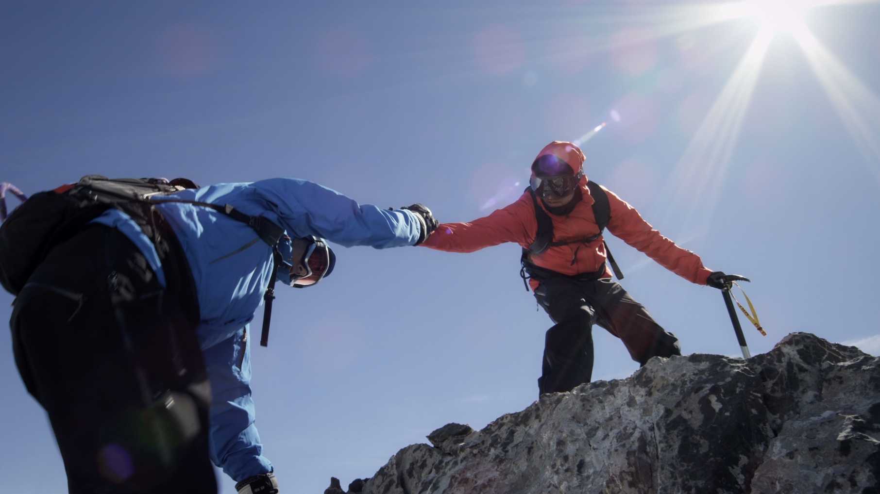 登山者在山上互相帮助翻越岩石